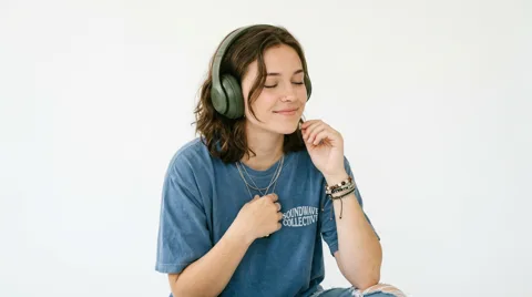 A woman smiling as she listens to music on her headphones